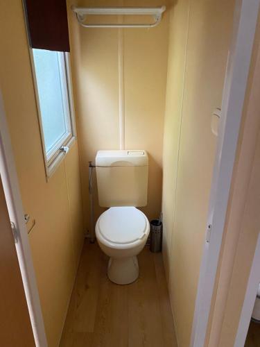a small bathroom with a toilet with a window at Mobil-Home standard in Voyennes