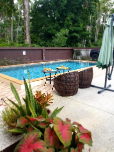 two tables and chairs next to a swimming pool at BSK Bungalows in Lipa Noi