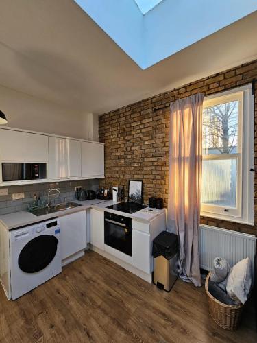 a kitchen with white appliances and a window at Putney Thames garden flat in London