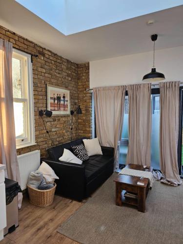 a living room with a black couch and a brick wall at Putney Thames garden flat in London