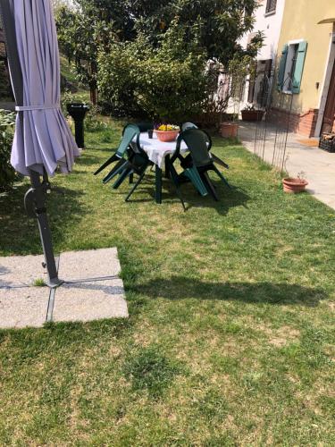 una mesa y sillas en un patio con sombrilla en Camera Privata Glicine, en Castellero