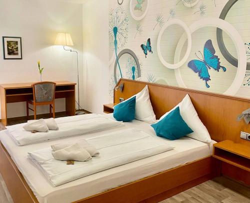2 Betten in einem Zimmer mit blauen Schmetterlingen an der Wand in der Unterkunft Hotel Krone Riesling in Trittenheim