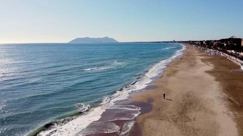 a beach with a person walking on the sand at Luxury Suite - Teatro Romano - Duomo - Centro Storico Wi-Fi in Terracina