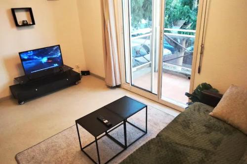 ein Wohnzimmer mit einem Sofa, einem TV und einem Tisch in der Unterkunft Votre chaleureux cocon proche Aéroport & Transport in Blagnac