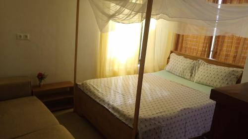 1 dormitorio con cama con dosel y ventana en Vue sur l'Atlantique, en Cotonou
