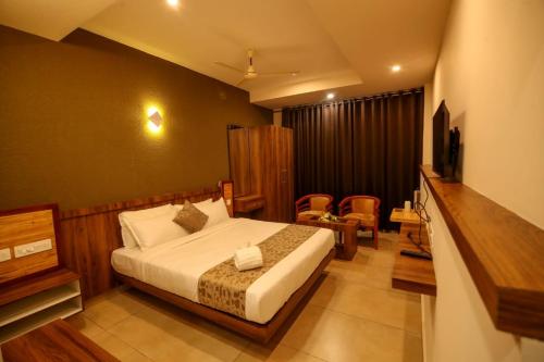 a hotel room with a bed and a television at ARIAT AVENUE in Wayanad