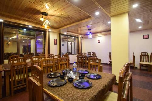 uma sala de jantar com mesa e cadeiras de madeira em Hotel Kalinga Grand - Top Rated Most Awarded Property In Manali em Manali