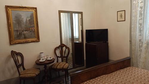 a bedroom with a bed and a television and a table at Relais Corso Storico in Pisa