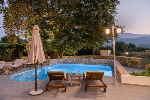 a swimming pool with a table and an umbrella at Villa Nature, Heated Pool in Kalyves