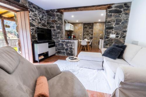 a living room with a white couch and a stone wall at Madeira Bird House - House in the Mountains With Garden in São Vicente