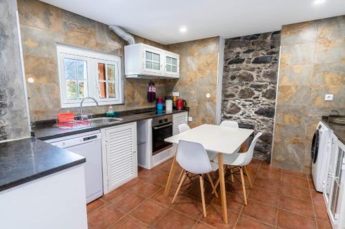 a kitchen with white cabinets and a table and chairs at Madeira Bird House - House in the Mountains With Garden in São Vicente