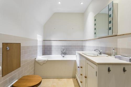 bagno con vasca, lavandino e specchio di Windrush a Colesbourne