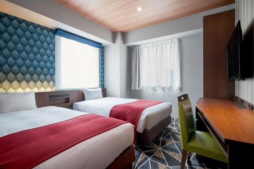 ein Hotelzimmer mit zwei Betten und einem Fernseher in der Unterkunft the b sapporo in Sapporo