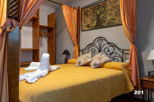a bedroom with a bed with yellow sheets and pillows at Hotel Uña Serranía Encantada in Uña