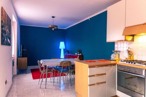 - une cuisine avec des murs bleus, une table et des chaises dans l'établissement Alle porte del Montefeltro - Maison Torriana, à Torriana