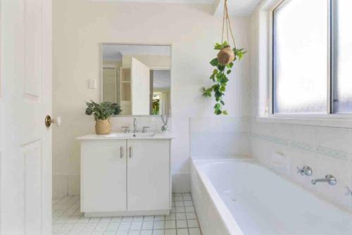 a white bathroom with a tub and a sink at Private Jetty Kayaks Pets allow WoyWoy Bay in Woy Woy