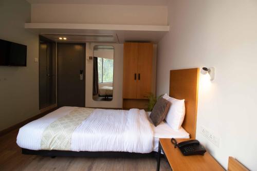 a bedroom with a bed and a desk with a phone at HOTEL LE ROYCE in Pune