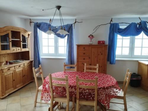 uma cozinha com mesa e cadeiras e cortinas azuis em Ferienwohnungen Bonnleiten Familie Stöger em Stössing