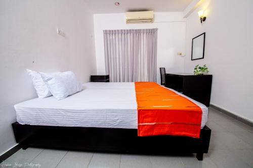 a bedroom with a bed with an orange and white blanket at Asian House in Colombo