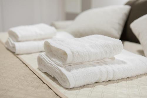 a pile of white towels sitting on a bed at Incantevole Loft - Centro Storico- Wi-Fi- Ad un passo da tutto in Terracina