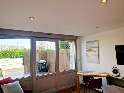 - un salon avec un bureau et une porte coulissante en verre dans l'établissement L'Instant Détente, à Barneville-Carteret
