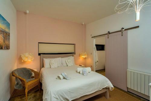 een slaapkamer met een groot wit bed en een stoel bij Finest Retreats - Sand Barn in Stalham