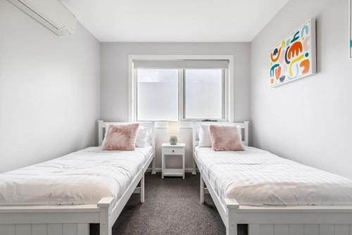 two beds in a room with a window at 'Caulfield Charm' Chic Inner-City Refuge in Melbourne