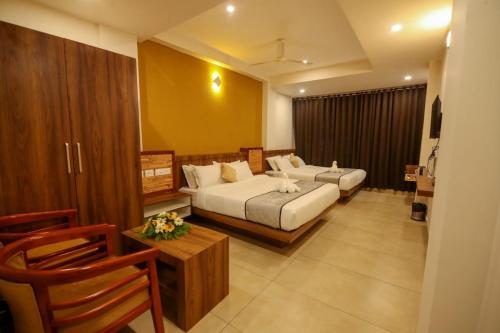 a hotel room with two beds and a table at ARIAT AVENUE in Wayanad