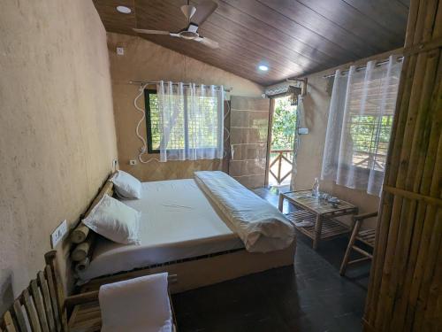 Athulyam Kanha, kanha national park, mukki gate في Khāpa: غرفة نوم صغيرة مع سرير وطاولة