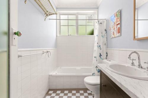 een badkamer met een bad, een toilet en een wastafel bij 'Elvira Rose' A Mid-Century Garden Sanctuary in Sydney
