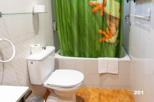 a bathroom with a toilet and a green shower curtain at Hotel Uña Serranía Encantada in Uña