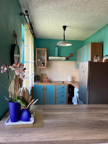 Studio tipa dzīvoklis في توكوموس: مطبخ مع دواليب زرقاء وطاولة مع ورد