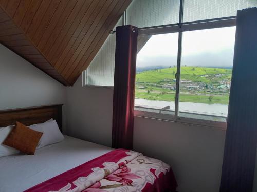 a bedroom with a bed and a large window at Creek View Inn in Nuwara Eliya