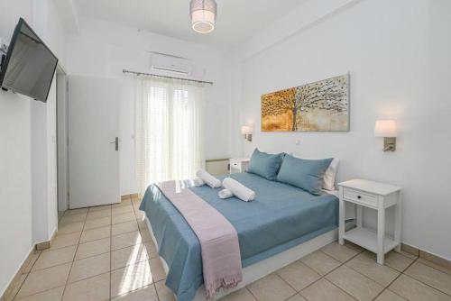 1 dormitorio con 1 cama azul y TV en Margarita's Kionia Beach House, en Kionia