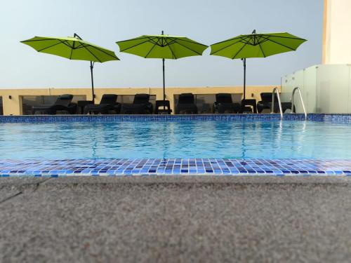 a swimming pool with chairs and umbrellas at Rosemond Al Hamra in Jeddah