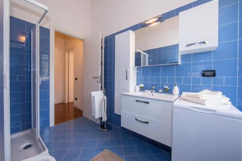 een blauwe betegelde badkamer met een wastafel en een douche bij BELLAGIO BALCONE in Bellagio