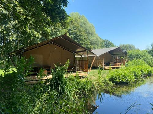 a large tent next to a body of water at Luxe safaritent aan het water - Recreatiepark de Uilenburg - Friesland - Sneek in Hommerts