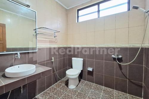 a bathroom with a toilet and a sink and a shower at Hotel Graha Muslim RedPartner in Bukittinggi