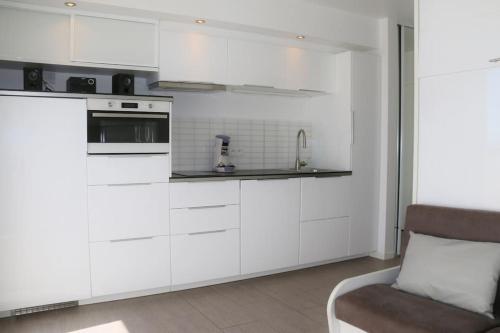 - une cuisine avec des placards blancs et un canapé dans l'établissement Studio 20, Héliopolis D au village naturiste, au Cap d'Agde