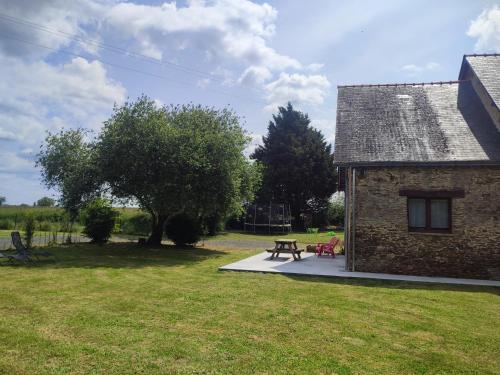 a picnic table in front of a stone building at Gîte La Pâquerie in Le Louroux-Béconnais