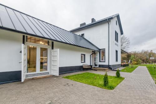 una casa bianca con tetto nero e cortile di Stacija Suntaži viesnīca 