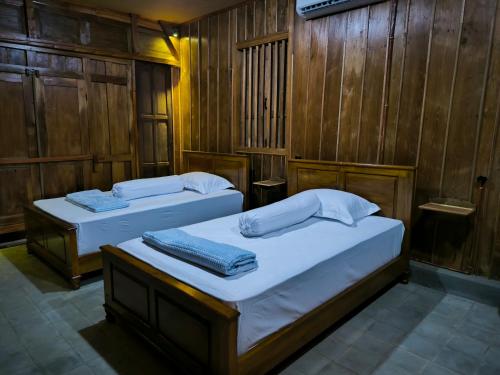 two beds in a room with wooden walls at Puri Swantari Javanese Home Stay in Sleman