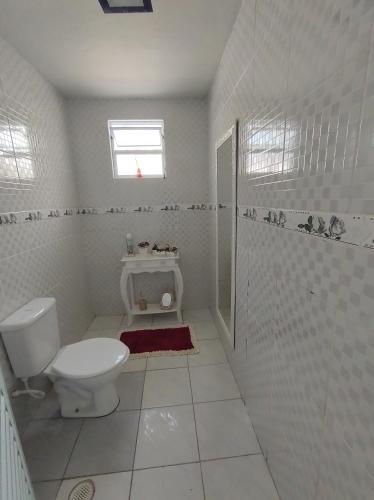 een witte badkamer met een toilet en een raam bij Casa com piscina in Peruíbe