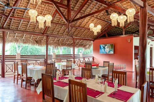 a restaurant with tables and chairs and chandeliers at Blue Sky Resort in Nosy Be