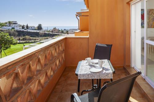 a table and chairs on a balcony with a view at Apartamento Baviera Golf 002 in Vélez-Málaga