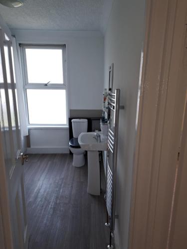 a bathroom with two toilets and a sink and a window at Nice Single Room near London Seven Kings Train station in London