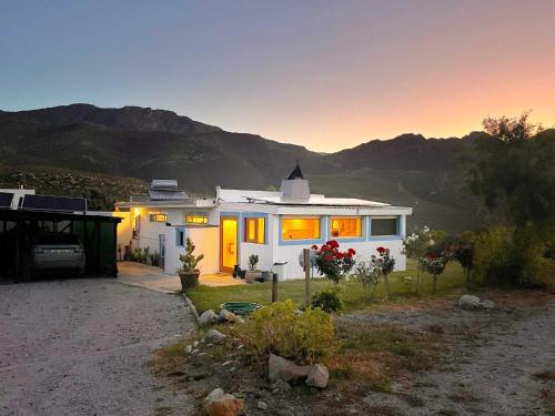 a small white house with mountains in the background at Starry Starry Night in Montagu