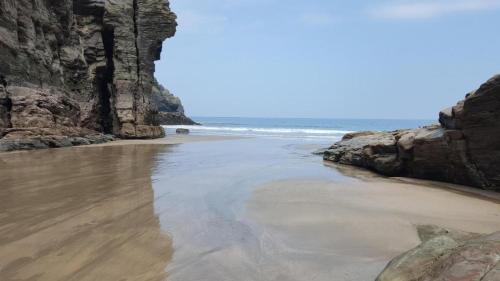 a beach with a rock wall and the ocean at Myrtle Cottage Boscastle in Boscastle