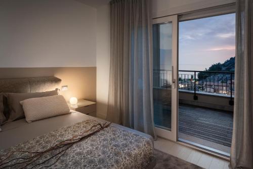 a bedroom with a bed and a large window with a balcony at Portopiccolo Apartments - Perla nel borgo in Sistiana