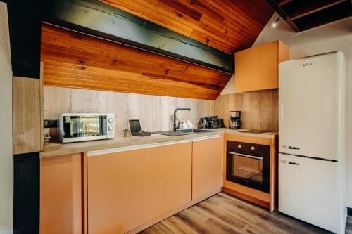 a kitchen with orange cabinets and a white refrigerator at Gîte Tribü in Eaux-Bonnes